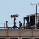 Police officers and other people stand near equipment on the rooftop of a building as the runway is reopened at London Gatwick Airport on December 21, 2018 in London, England.